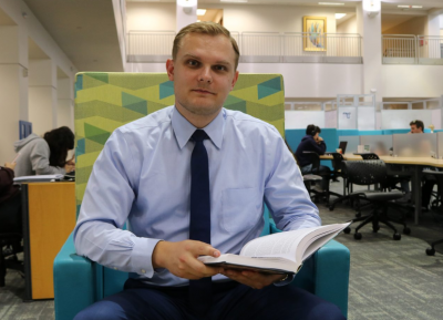 Dorian Zwierewicz sitting in a chair with a book.