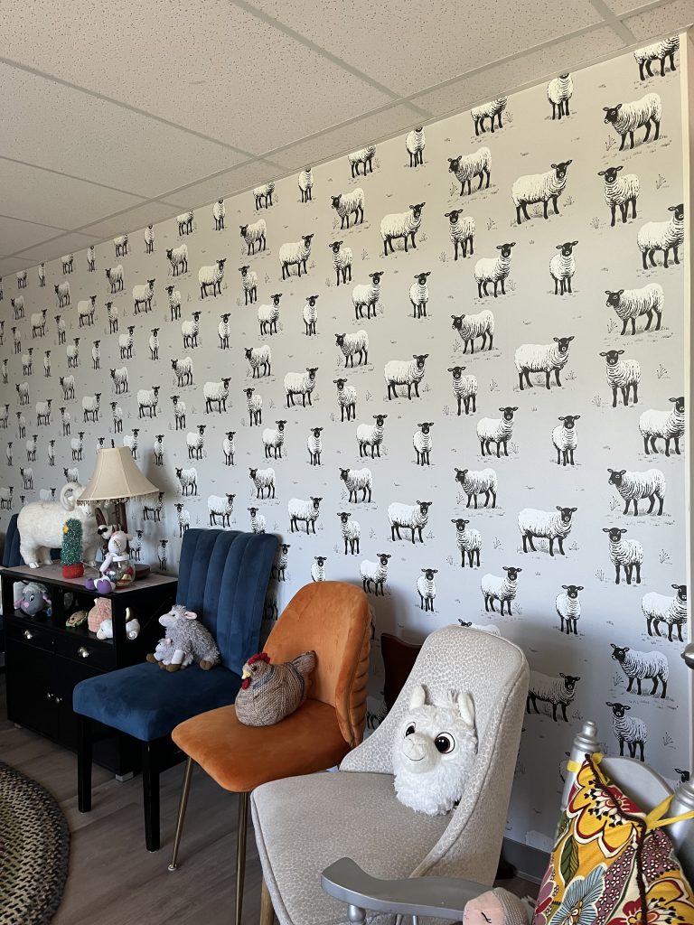Colorful chairs against a wall with sheep wallpaper