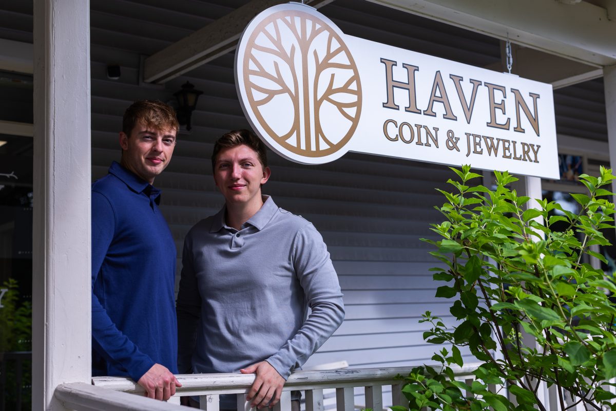 The owners of Haven Coin & Jewelry next to their sign